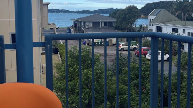 Ein Balkon mit Blick auf ein Gewässer, einen Parkplatz und umliegende Gebäude.