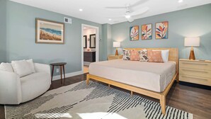 Une chambre à coucher comprenant un lit, des tables de chevet, une commode, un canapé, un tapis et des œuvres d’art accrochées aux murs.