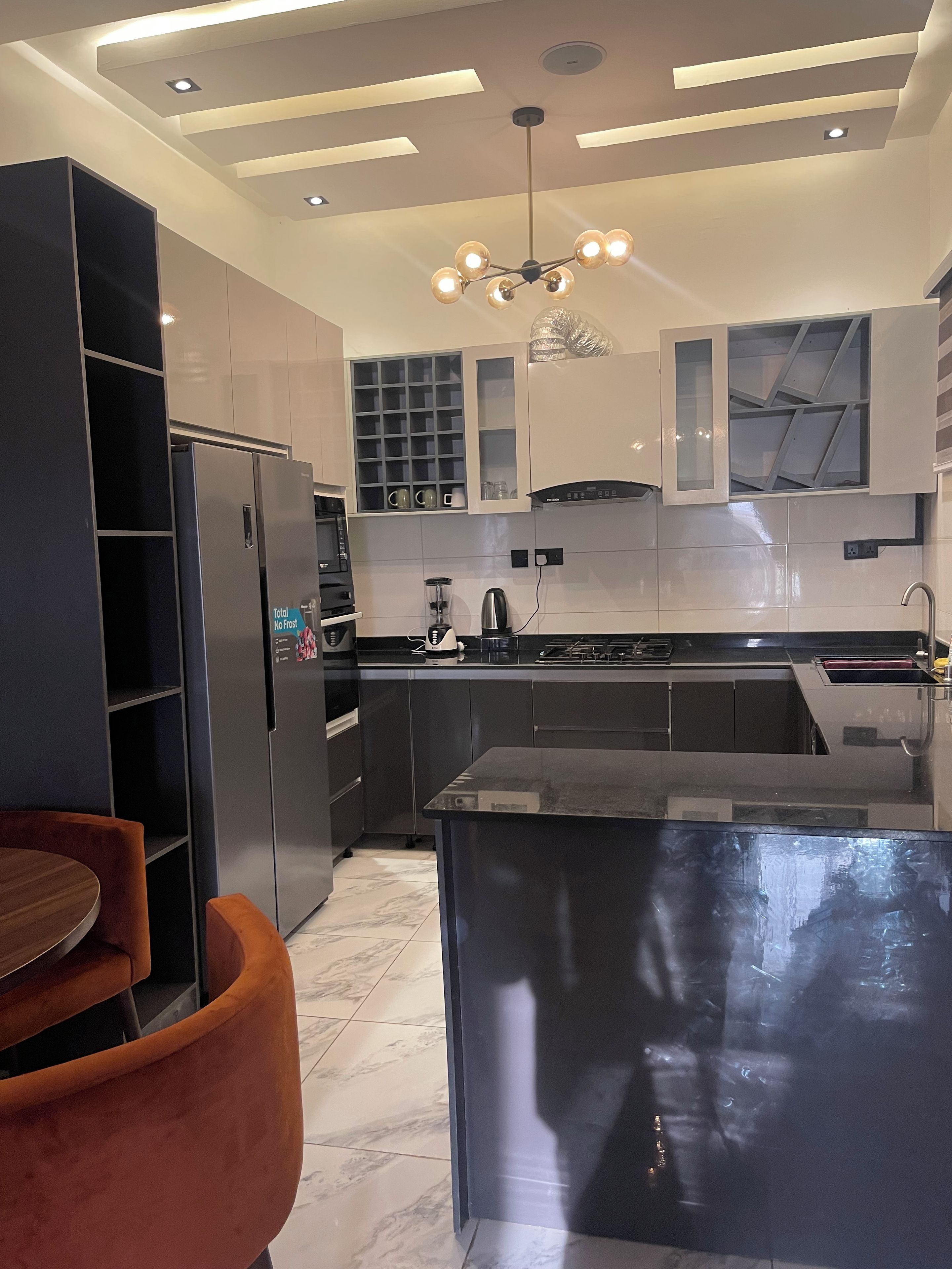 A modern kitchen with a central island, built-in appliances, and a dining area with a round table and chairs.