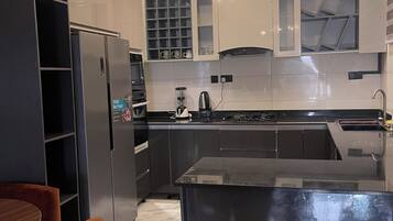 A modern kitchen with a central island, built-in appliances, and a dining area with a round table and chairs.