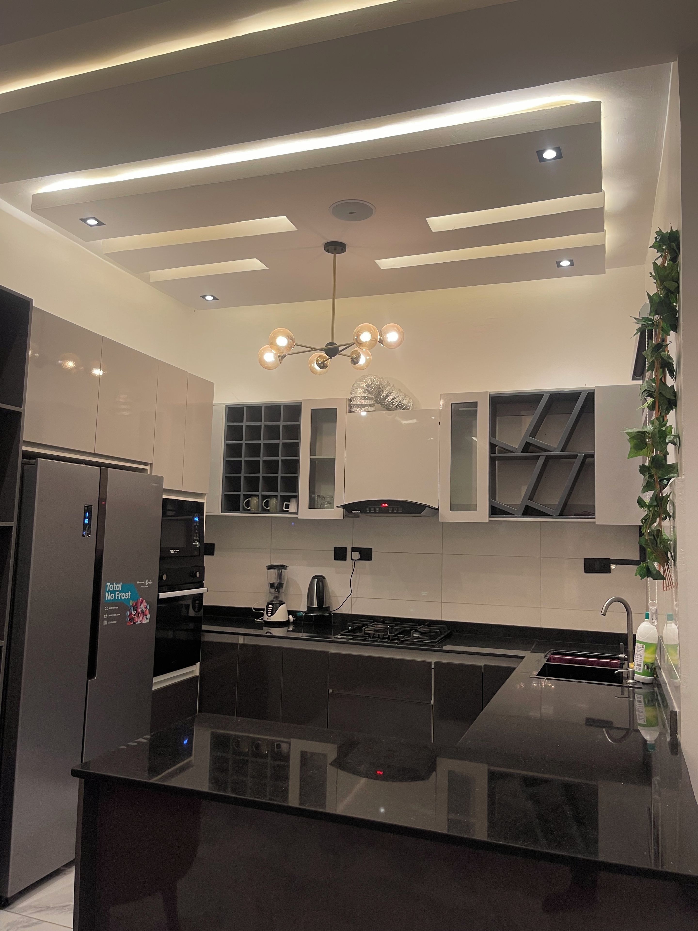 Una cocina moderna con una isla central, electrodomésticos integrados e iluminación contemporánea.