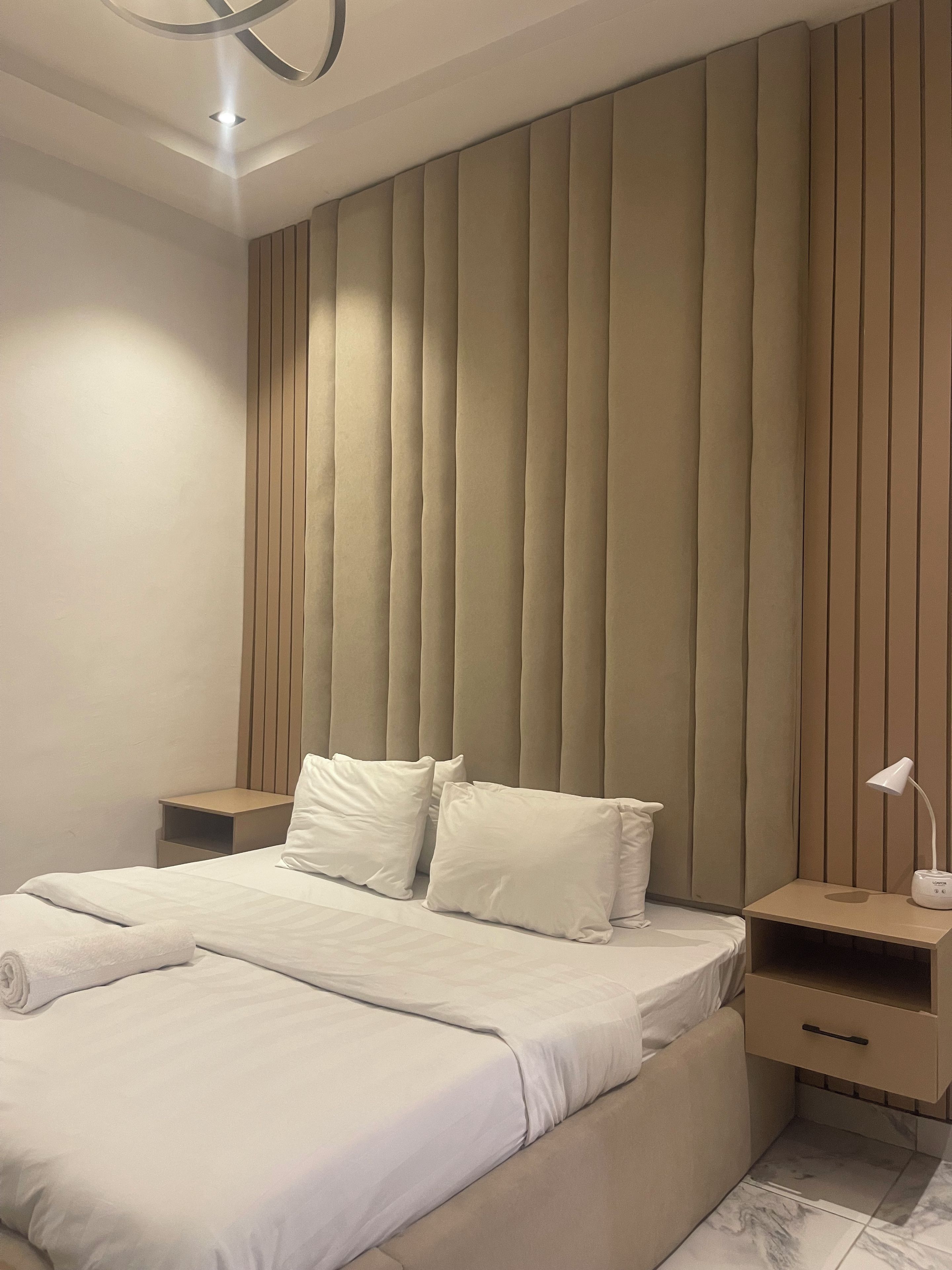 Una camera da letto moderna con un letto grande, due comodini e una testiera con pannelli verticali.