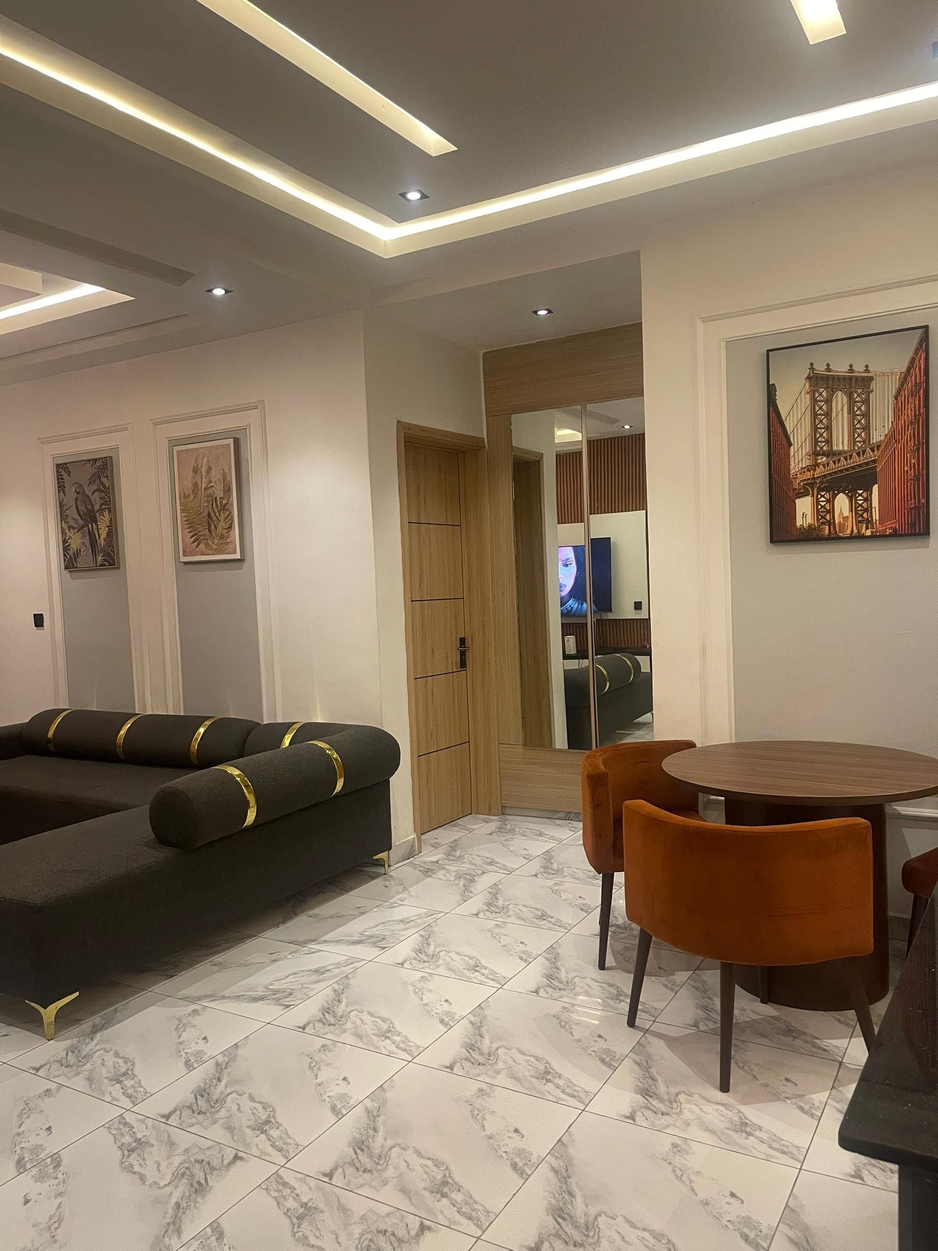A modern living room with a sectional sofa, a dining table with chairs, and a large mirror reflecting the room.