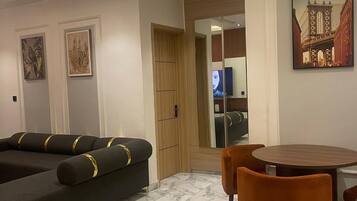 A modern living room with a sectional sofa, a dining table with chairs, and a large mirror reflecting the room.