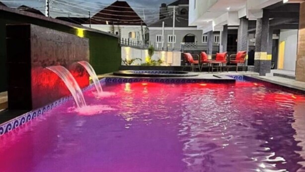 A swimming pool with a water feature, surrounded by buildings with balconies. - Snowdrop Apartments  (Lekki)