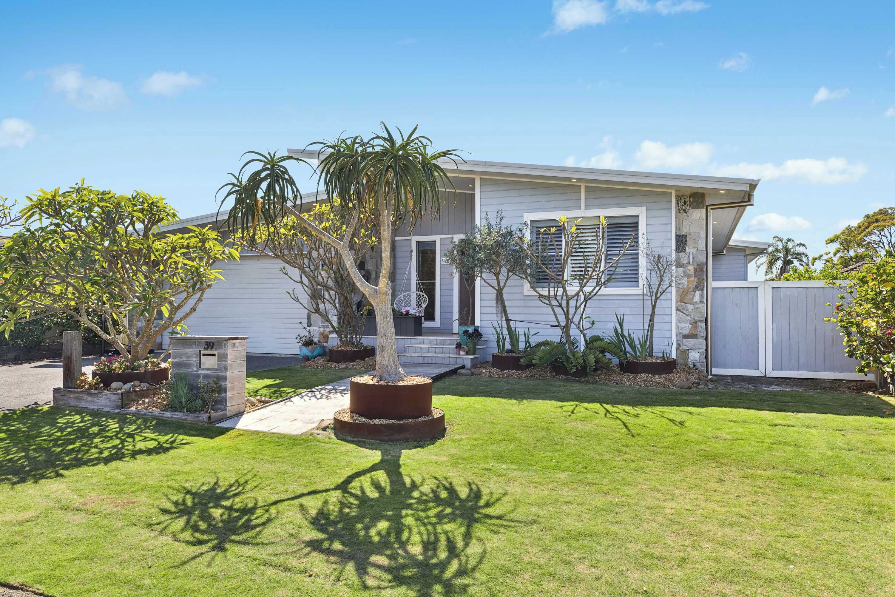 A single-story house with a well-maintained lawn and several potted plants.