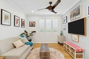 Ein Wohnzimmer mit einer Couch, einem Couchtisch, einem Fernseher und Kunstwerken an den Wänden.