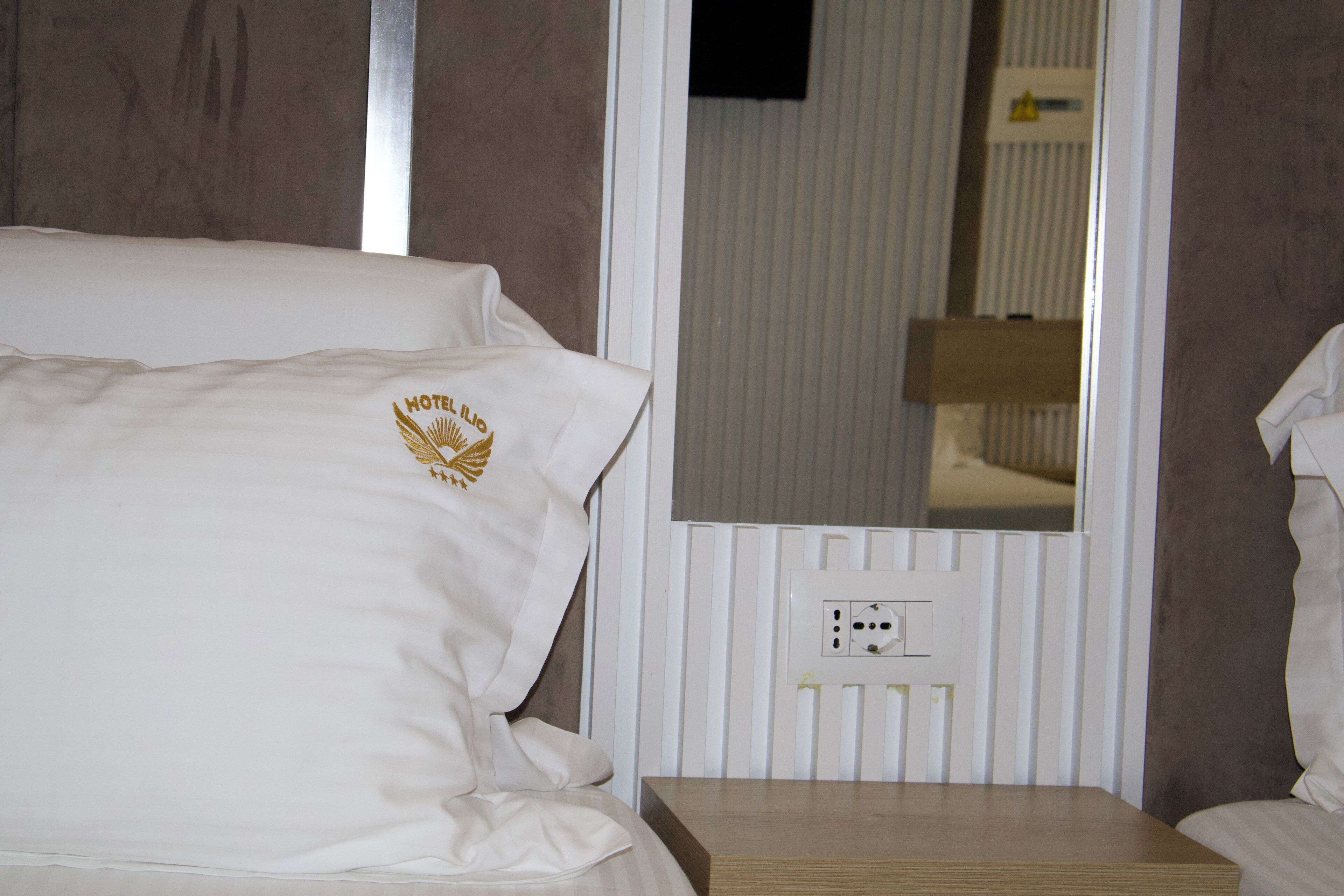 Ein Hotelzimmer mit Bett, Nachttisch und einem am Wand montierten Fernseher.