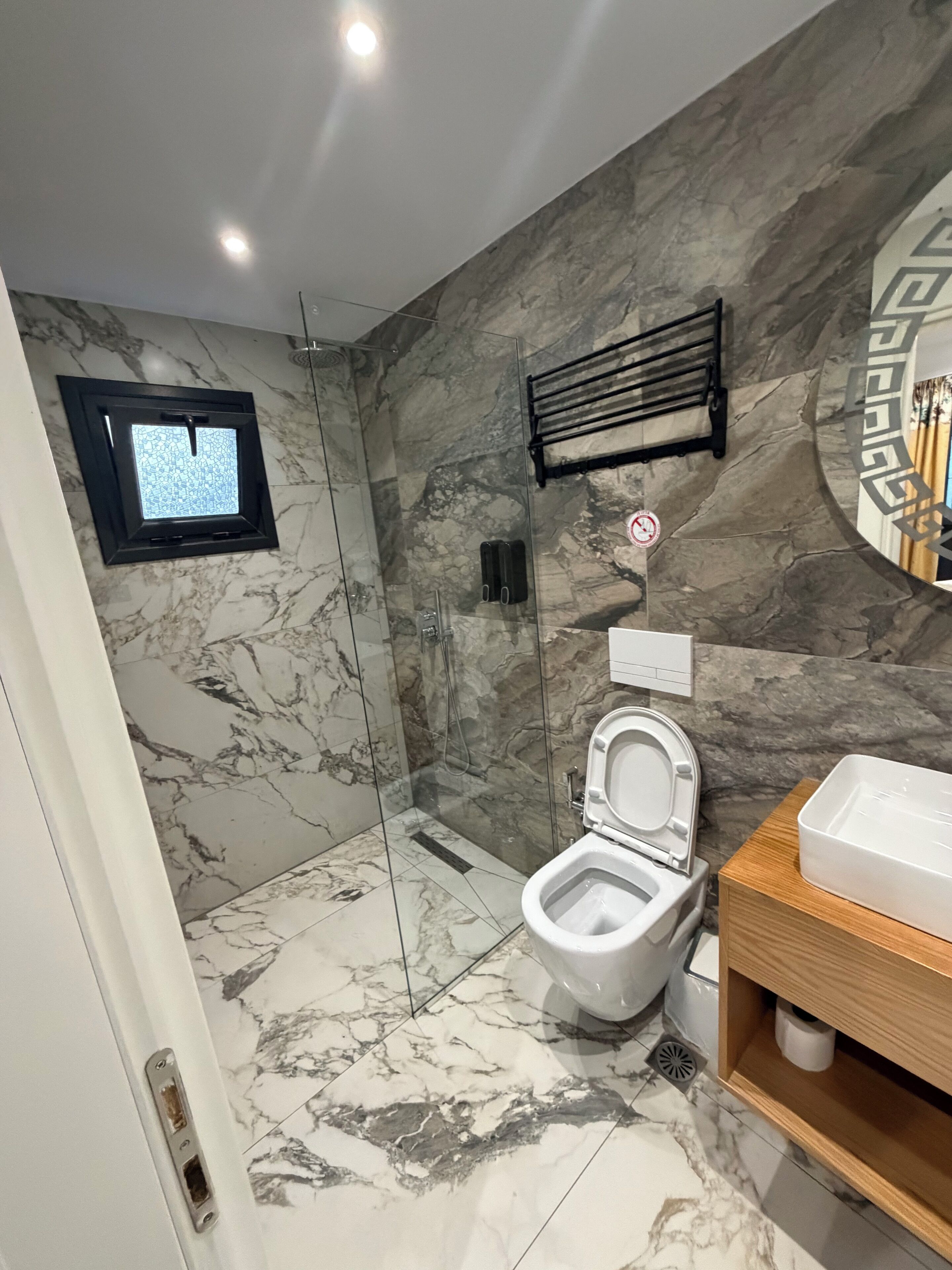 A modern bathroom with a glass-enclosed shower, a toilet, and a sink.