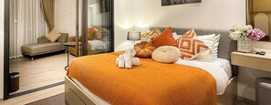 Una habitación de hotel con cama, sofá, lámpara y un florero con flores.