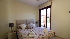 Ein Schlafzimmer mit Bett, Nachttischen und Blick durch eine Glastür.