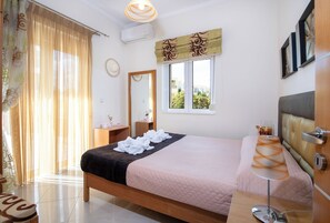 Un dormitorio ordenado con cama, mesita de noche, lámpara y ventana con cortinas.