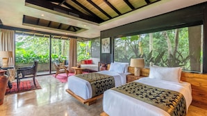 A modern hotel room with two beds, a sitting area, and large windows offering a view of the outdoors. - Yara Wellness (Buwit)