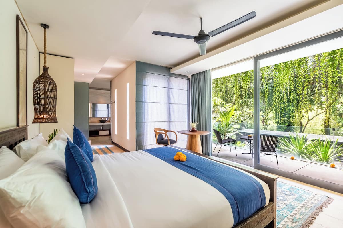 Ett modernt hotellrum med en stor säng, en takfläkt och utsikt över omgivningarna.