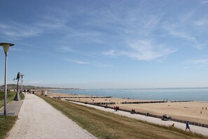 Ein Küstenweg, der zu einem Strand mit blauem Himmel führt.