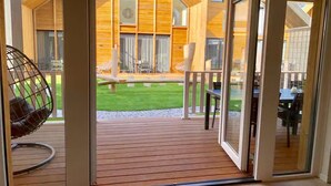 Une terrasse en bois avec une porte vitrée donnant sur un espace extérieur aménagé avec une table et des chaises.