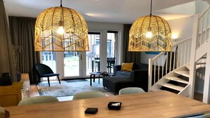Un salon moderne avec une table à manger en bois, des chaises bleues, un canapé noir et un escalier.