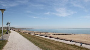 Een kustpad dat naar een strand leidt, onder een heldere lucht.