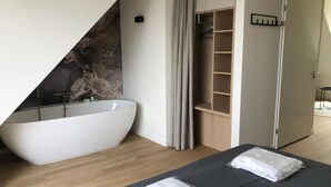 A modern bathroom with a freestanding bathtub, a wooden vanity, and a walk-in shower. - 2-person lodge on 2nd floor with view of dunes. (Zoutelande)
