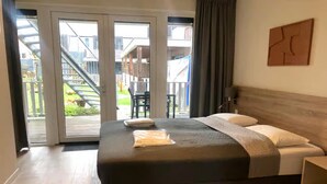 A bedroom with a large bed, a view of a staircase and outdoor area, and a wooden headboard. - Lodge with beautiful view of the church and dunes. (Zoutelande)
