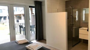 A modern bathroom with a glass shower enclosure, a white sink, and a large mirror. - Beautiful lodge suitable for 2 people. (Zoutelande)