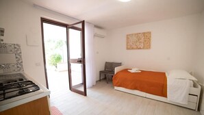 Une chambre compacte comprenant un lit, une petite table et un coin cuisine.