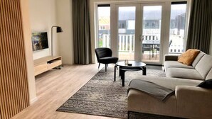 Ett modernt vardagsrum med en soffa, ett soffbord, en tv och en fåtölj.