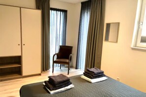 A hotel room with a bed, a chair, a wardrobe, and a window with curtains. - Apartment by the dunes in Zoutelande (Zoutelande)