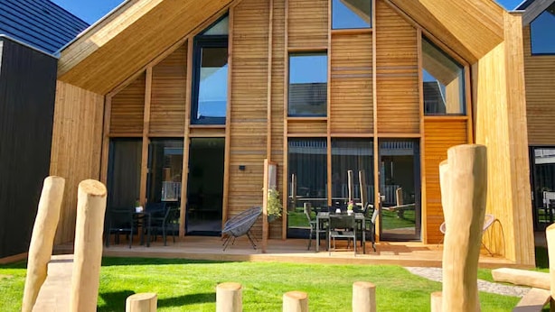 A modern wooden house with large windows and a patio area. - 4-person luxury lodge in Zoutelande (Zoutelande)