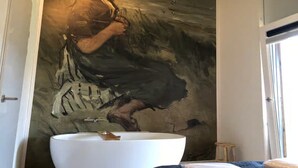 A bathroom with a large abstract painting on the wall, a white sink, and a small stool. - 4-person luxury lodge in Zoutelande (Zoutelande)
