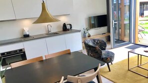 Cuina moderna amb armaris blancs, taule negra i una làmpada penjant.