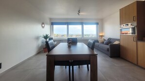 Et moderne opholdsrum med spisebord, sofa og køkkenafsnit.