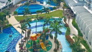 Un hotel moderno con numerosi balconi, una piscina centrale e un'area giochi per bambini.