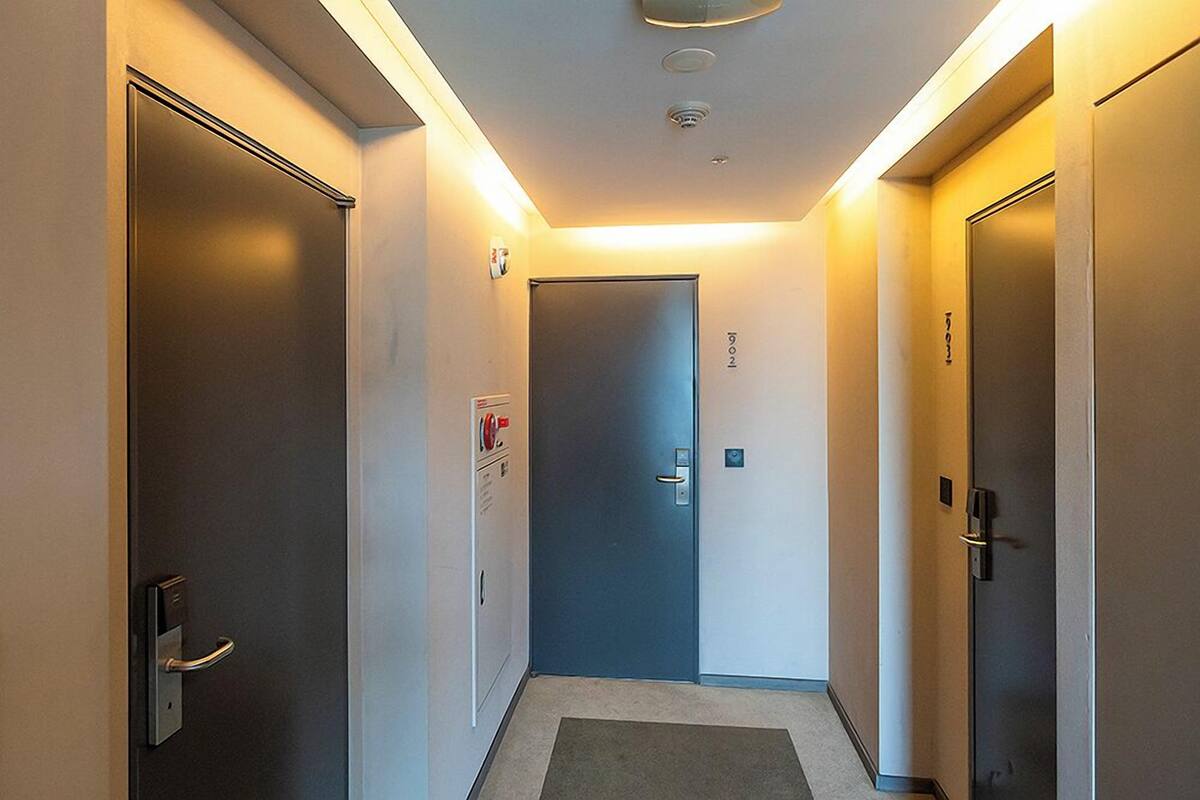 A hallway with doors on both sides, a carpeted floor, and a ceiling light fixture.