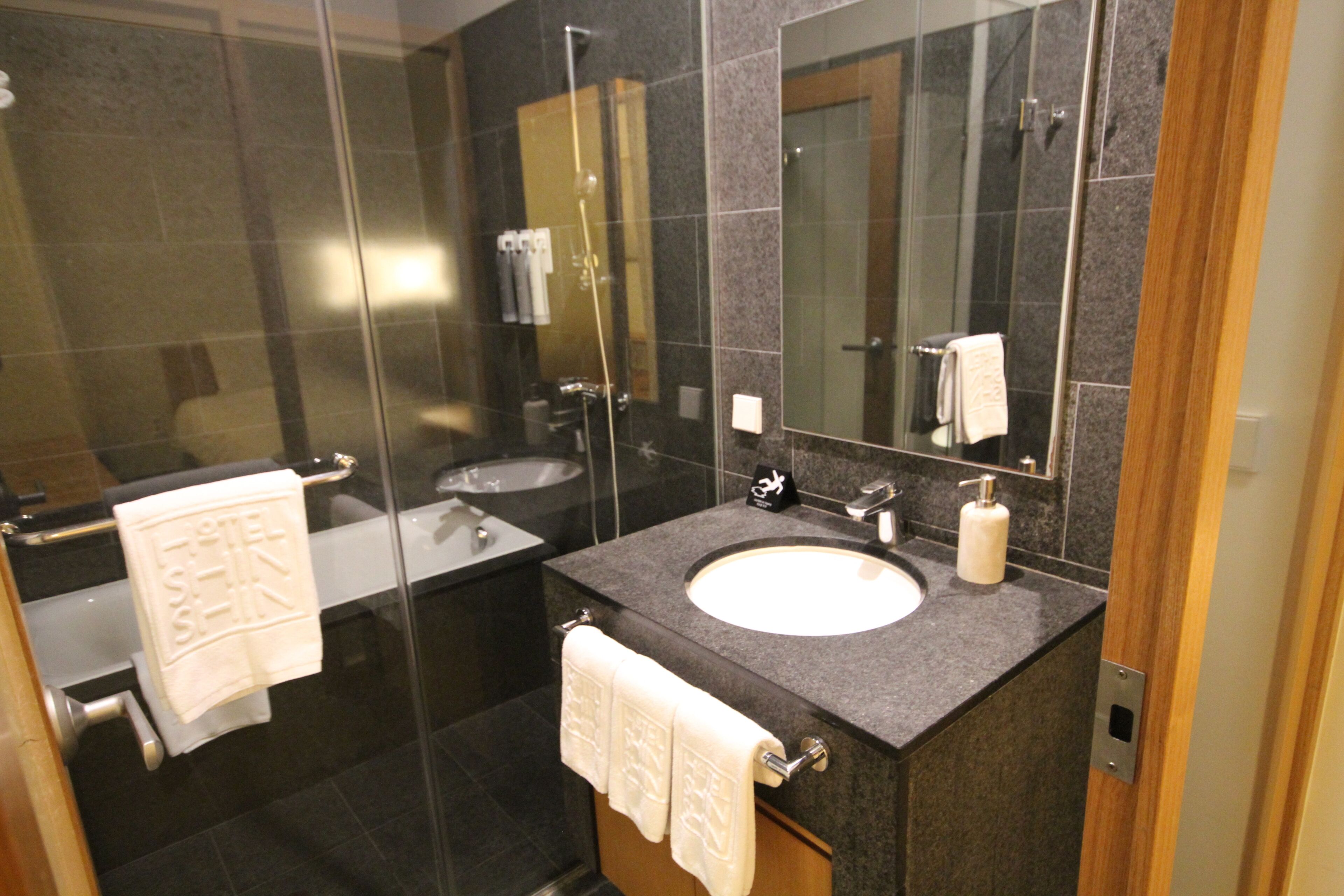 A modern bathroom with a glass shower enclosure, a double sink vanity, and a large mirror.