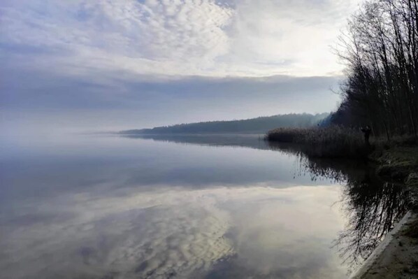 A calm lake with a clear reflection of the sky and trees on the water's surface.