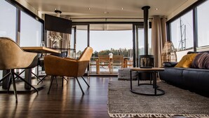 Ein modernes Wohnzimmer mit Sofa, Sesseln, Couchtisch und Fernseher.