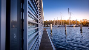 Een houten terras dat over het water uitloopt, met een rij bootjes afgemeerd in de verte.