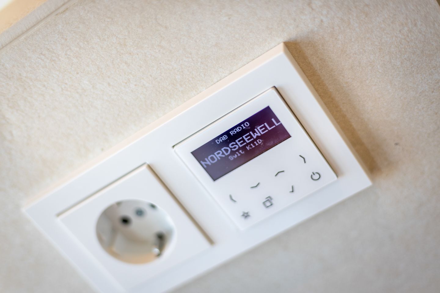 Ein Thermostat mit digitaler Anzeige, Bedienfeld und Steckdose.