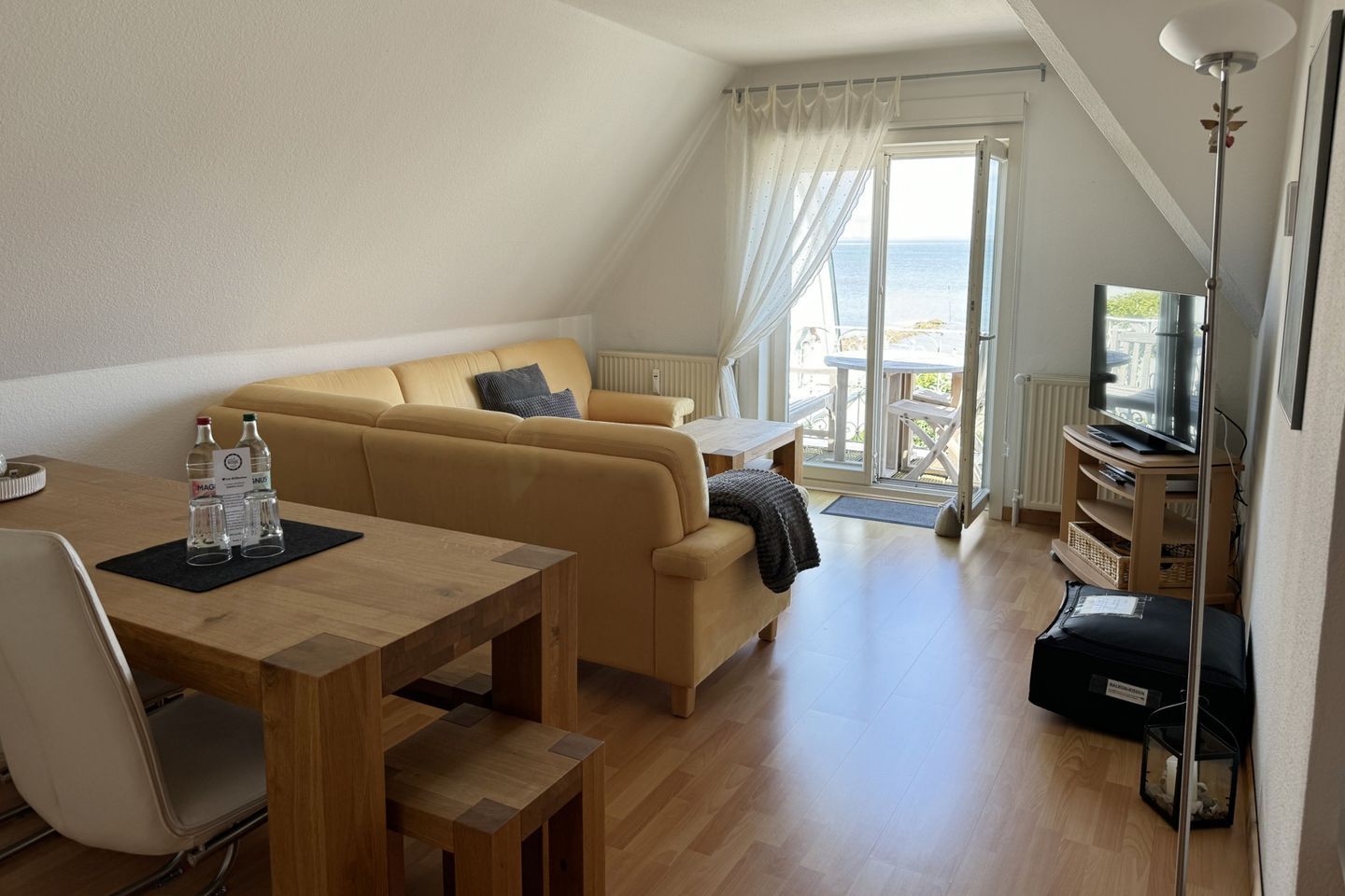 Un soggiorno moderno con divano, tavolo da pranzo, televisore e un balcone con vista.