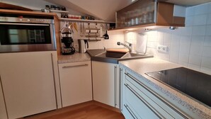 A compact kitchen with a built-in oven, a coffee maker, and a sink. - Sandwall 14, Whg. 6, Sandwallkoje - Holiday apartment with 3 rooms on the Sandwall (Wyk auf Föhr)