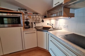 Eine kompakte Küche mit Backofen, Kaffeemaschine und Spüle.