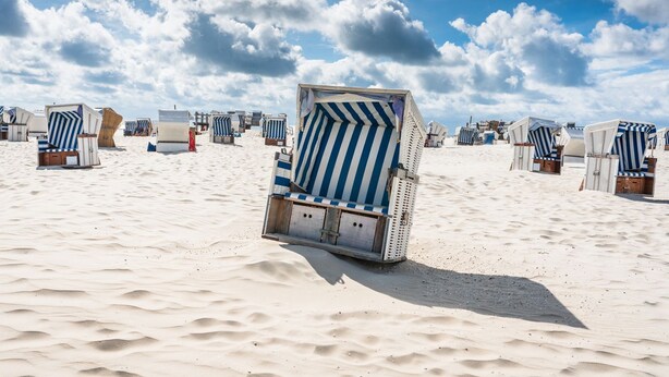 A beach with rows of striped beach chairs and umbrellas. - Apartment Turmblick - Comfortable apartment in the center of Marienhafe with (Marienhafe)