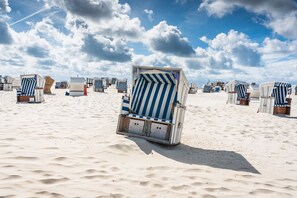 A beach with rows of striped beach chairs and umbrellas. - Apartment Turmblick - Comfortable apartment in the center of Marienhafe with (Marienhafe)