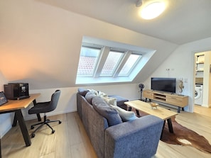 A modern loft apartment with a skylight, a sofa, a coffee machine, a TV, and a washing machine. - Apartment Turmblick - Comfortable apartment in the center of Marienhafe with (Marienhafe)