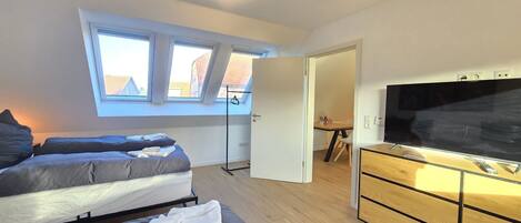 A bedroom with two beds, a TV, and a wooden dresser.