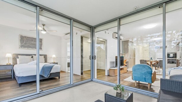 Een moderne hotelkamer met een groot bed, een bureau, een stoel en een glazen scheidingswand.