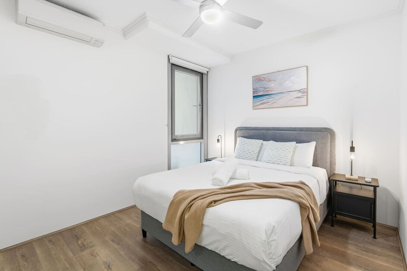 A modern bedroom with a bed, bedside table, and a ceiling fan.