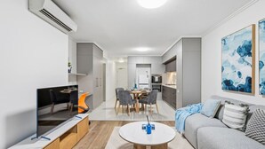 Een moderne woonkamer met een televisie, bank en eethoek.