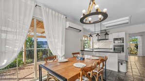 Una cocina moderna con comedor, ventanas amplias y vistas a la vegetación.